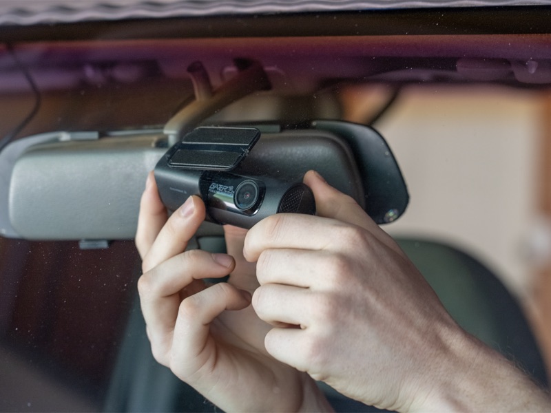 Dash cam being installed near the rear-view mirror of a vehicle